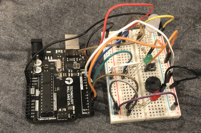 a picture of a breadboard with red, green, and RGB LEDs, as well as a Piezo buzzer attached to an Arduino Uno